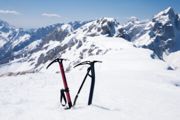 Two ice axes in the snow at the summit of the mountain.