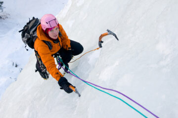 Woman ice climbing a massive ice sheet.