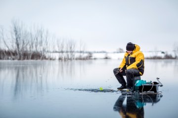 Fisherman sitting ice fishing on a lake.