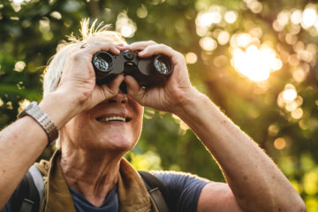 Old man using binoculars for bird watching